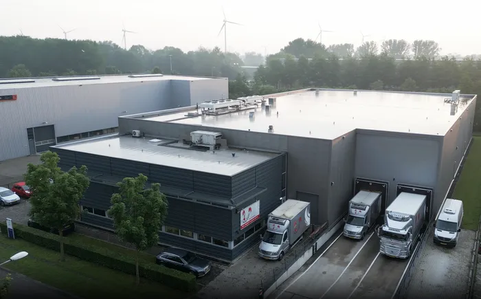 Luchtfoto van bedrijfspand J. van de Kraats Kipspecialiteiten. Voorzijde met vrachtwagens voor de docks.